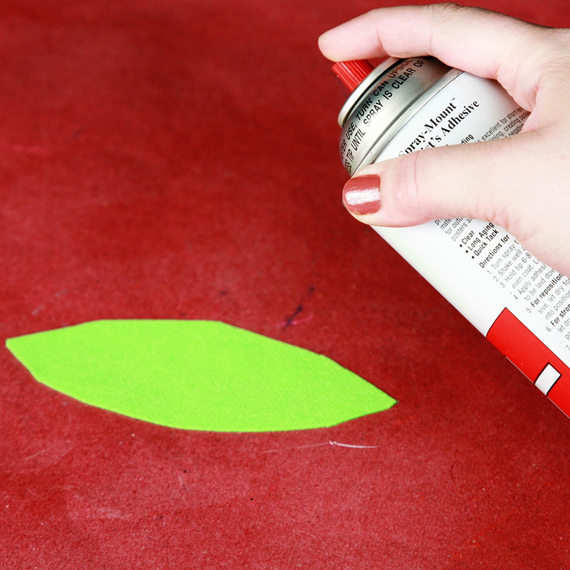 A hand us aiming a spray bottle at a piece of bright green spandex.