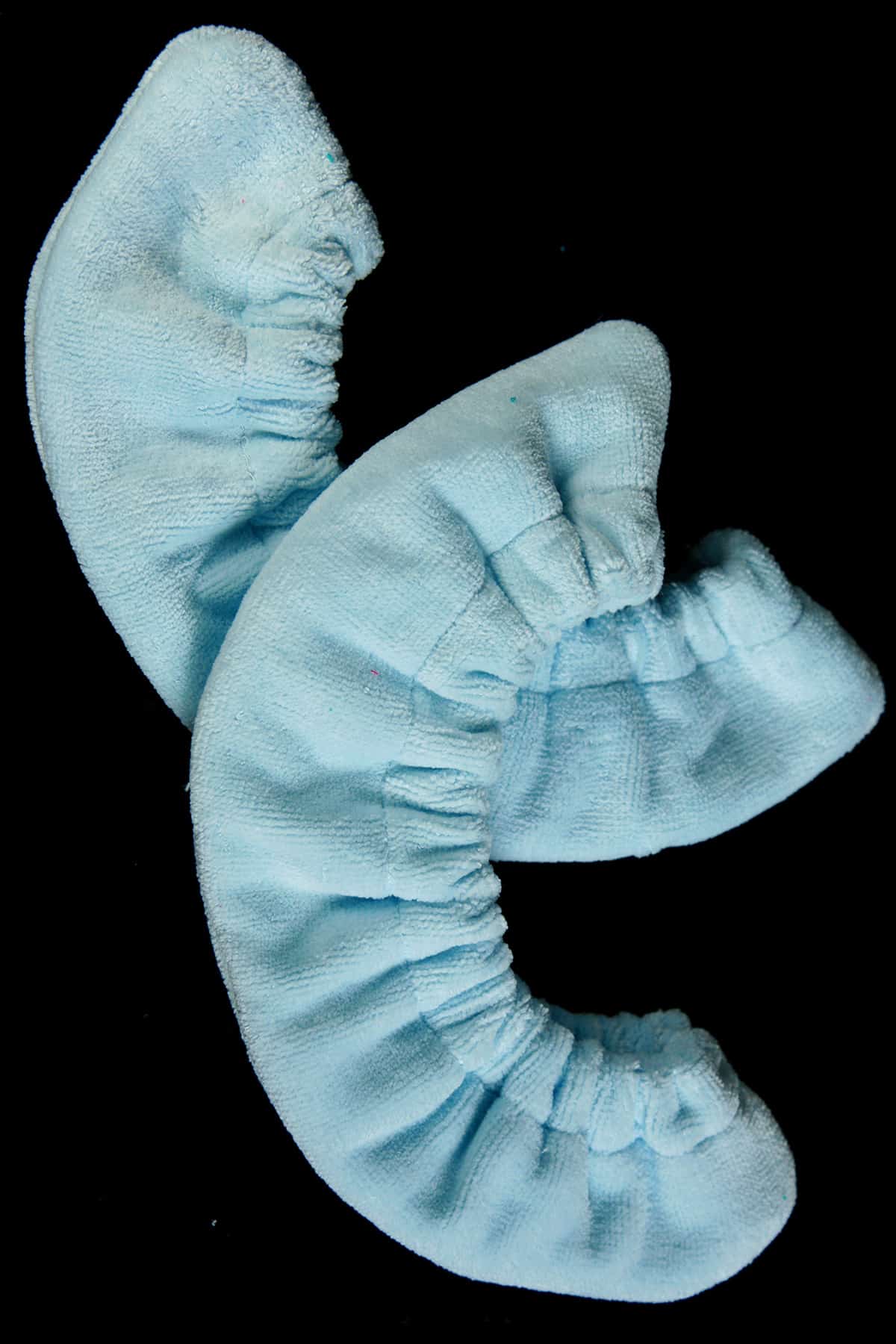 A pair of light blue terrycloth soakers against a black background.