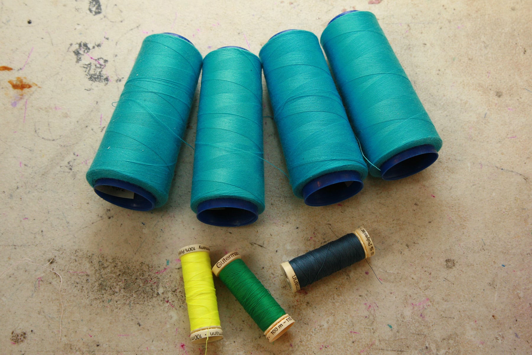 A selection of thread spools in various colours are shown on a work table.