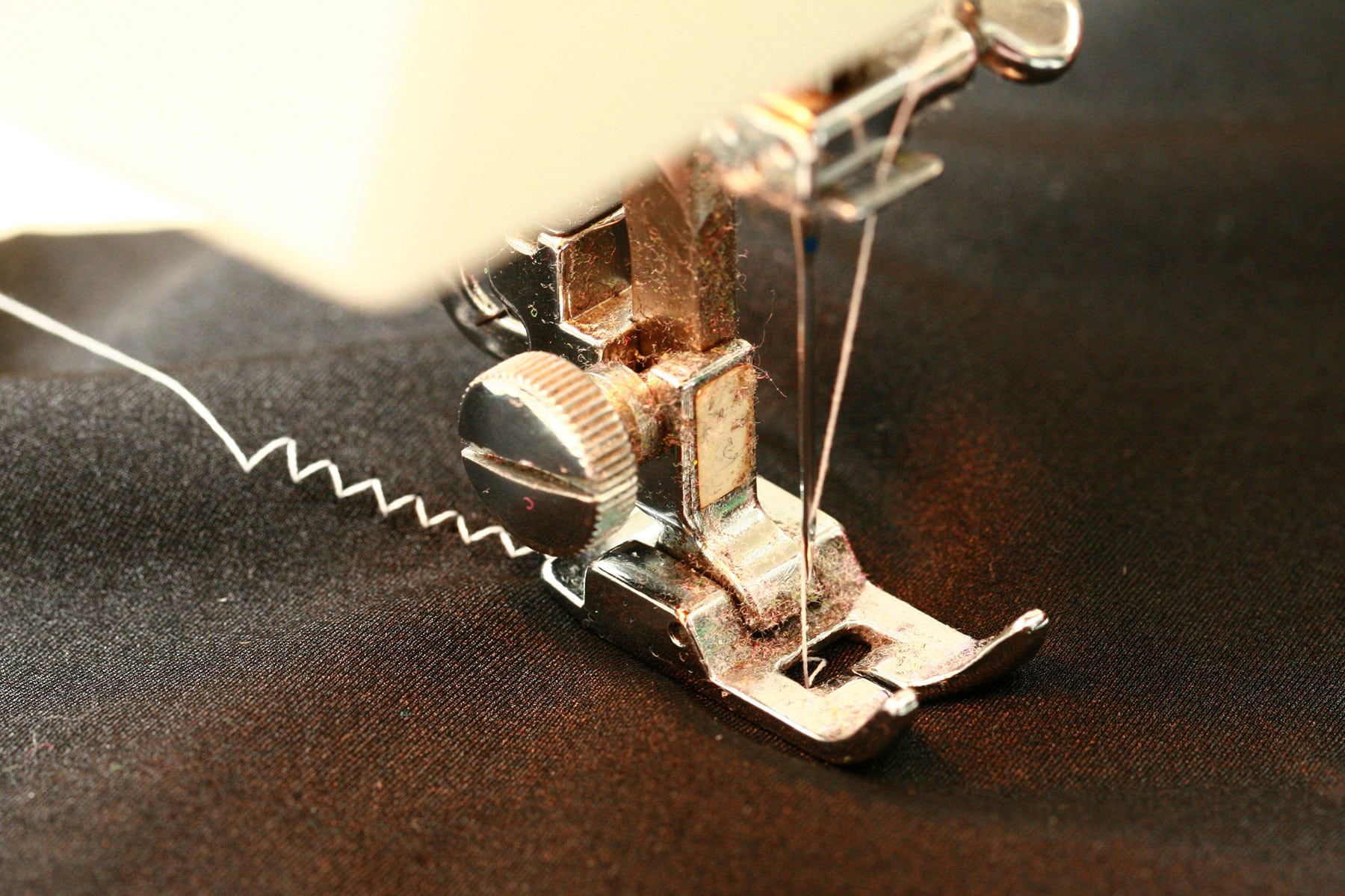 A close up view of a sewing machine sewing spandex with a zig zag stitch.