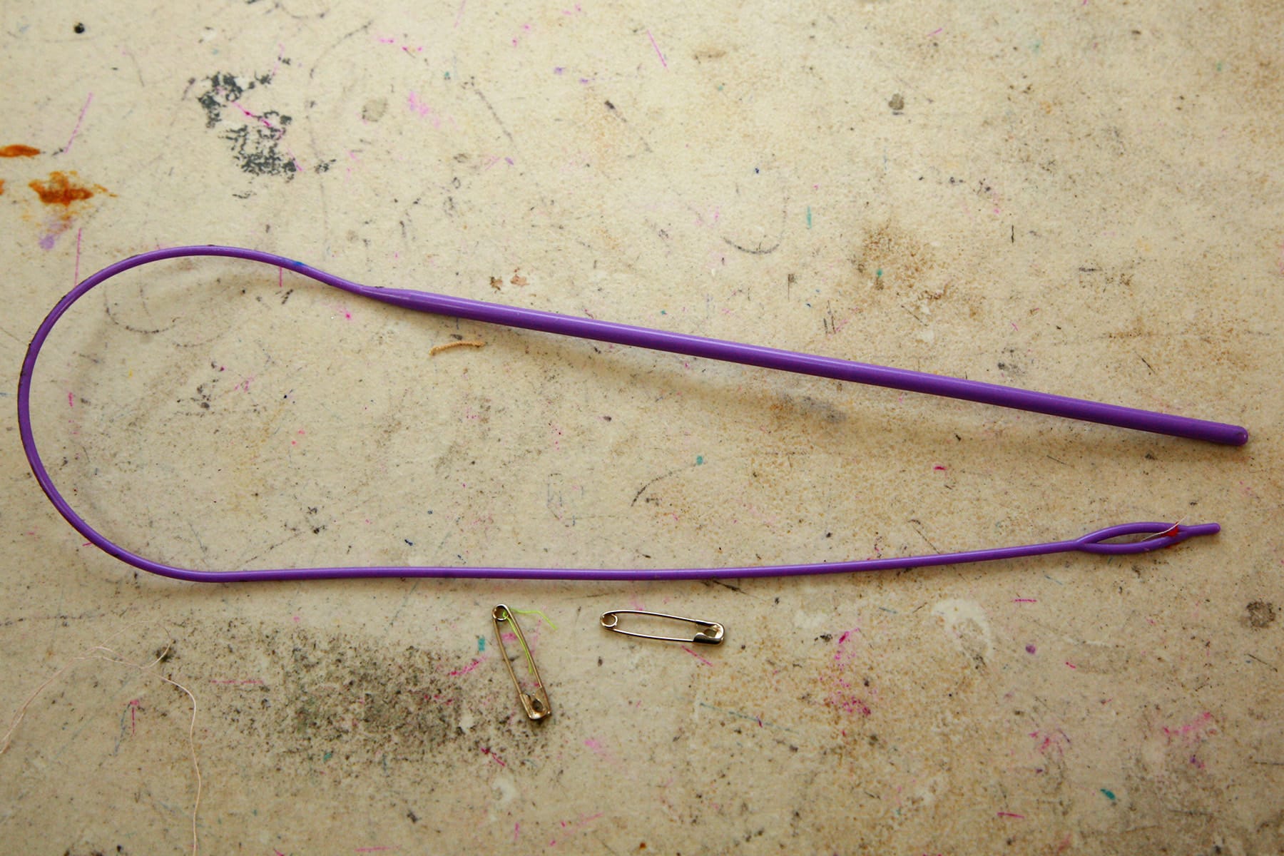 A purple cord threader is laid out on a work table.
