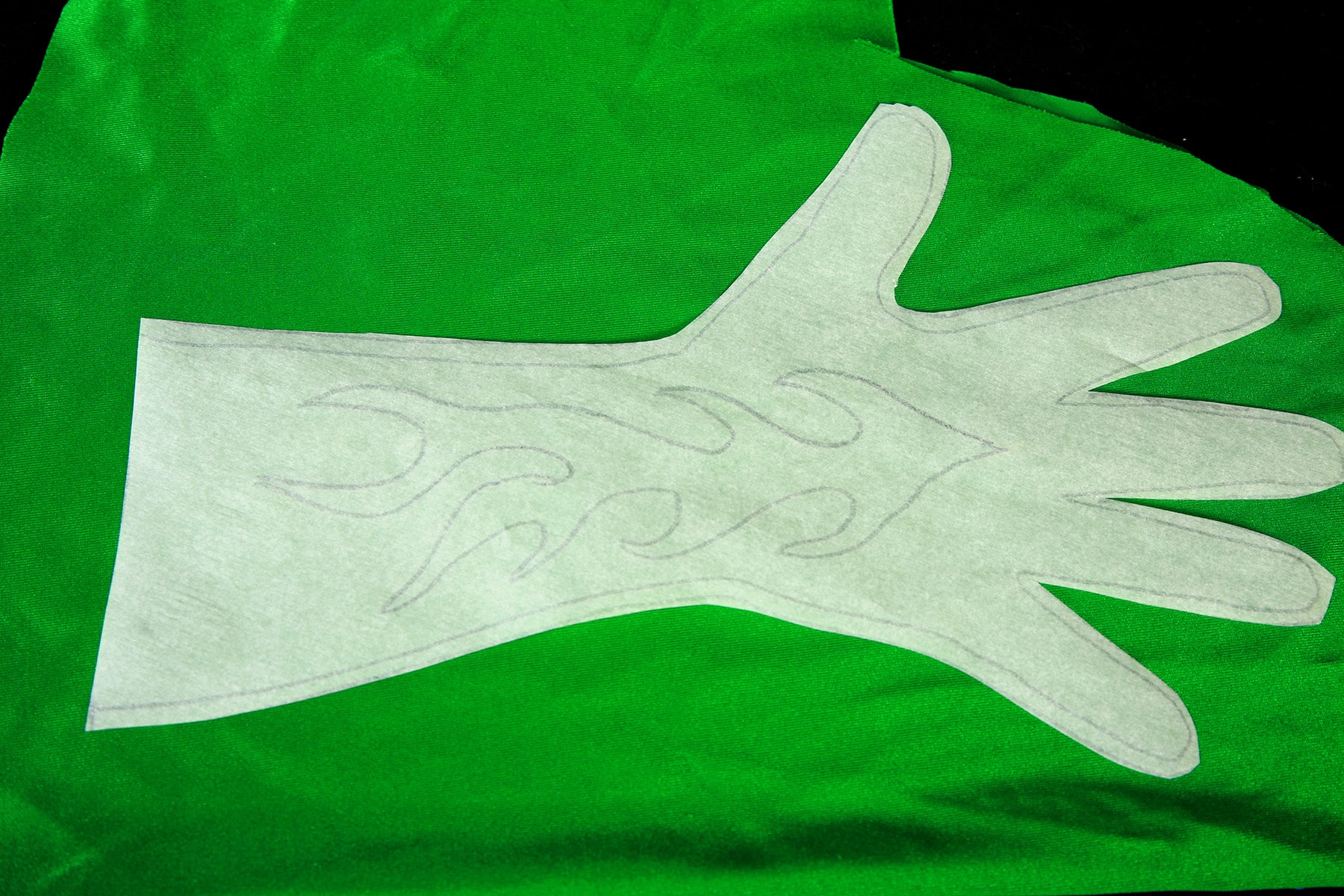 The paper glove pattern rests on top of the darker green spandex.
