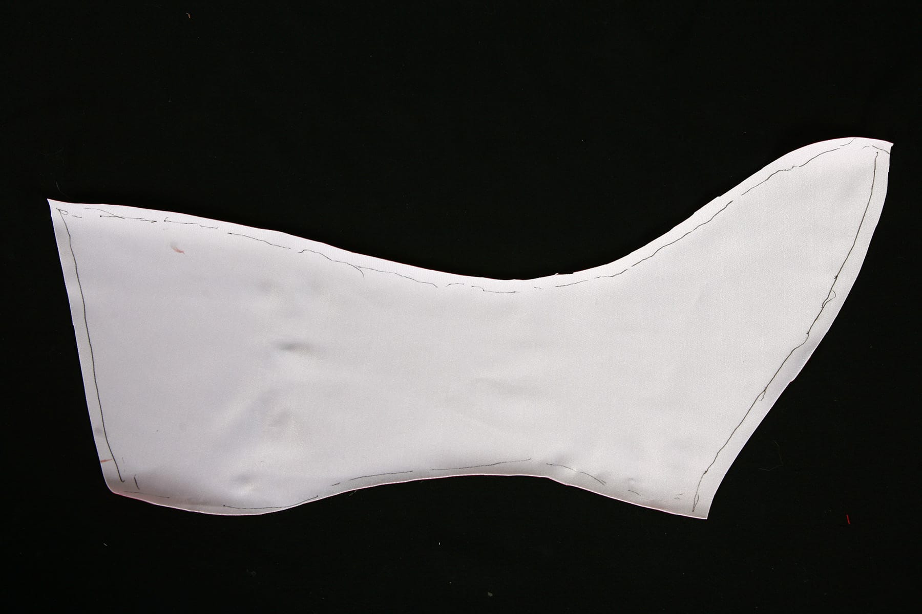 White fabric in the shape of a boot cover, against a black background.
