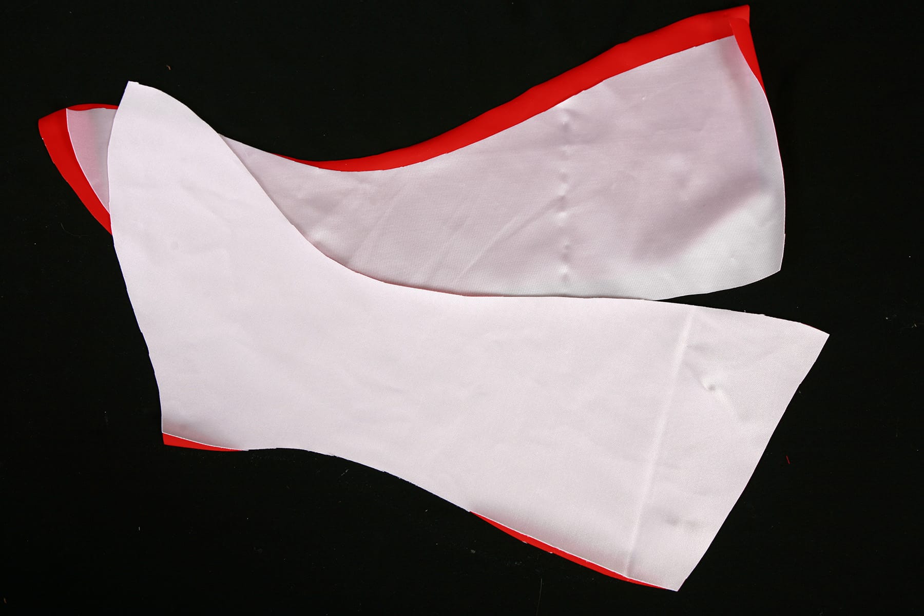 Two boot covers cut from red and white fabric, against a black background.