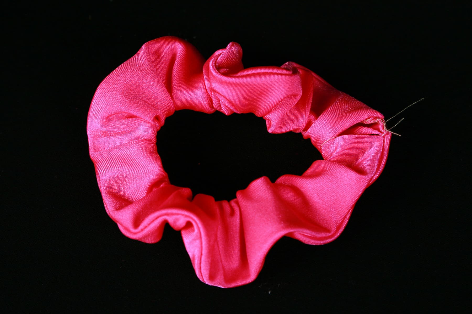 A close up image of a hot pink spandex scrunchie.