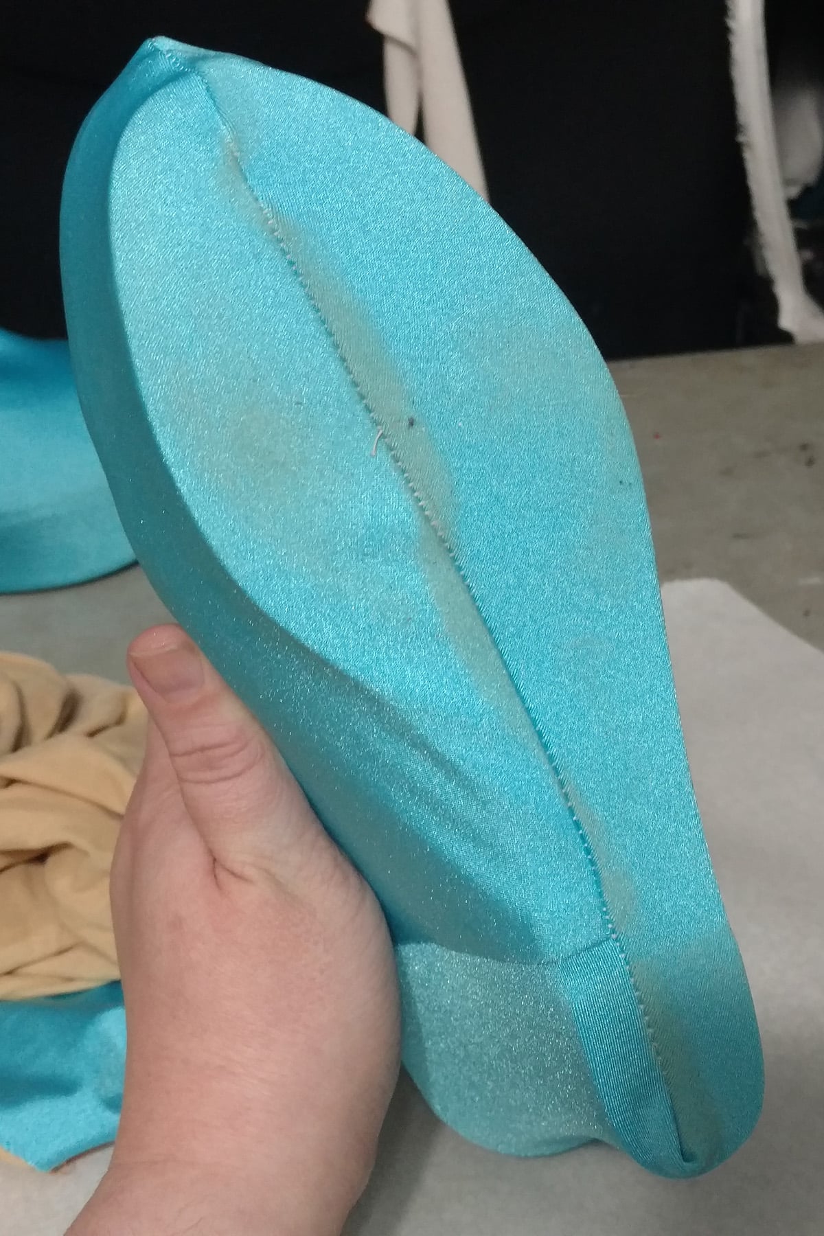 A hand holds up a spandex covered shoe. It's light blue, and showing some signs of dirt/scuffing.