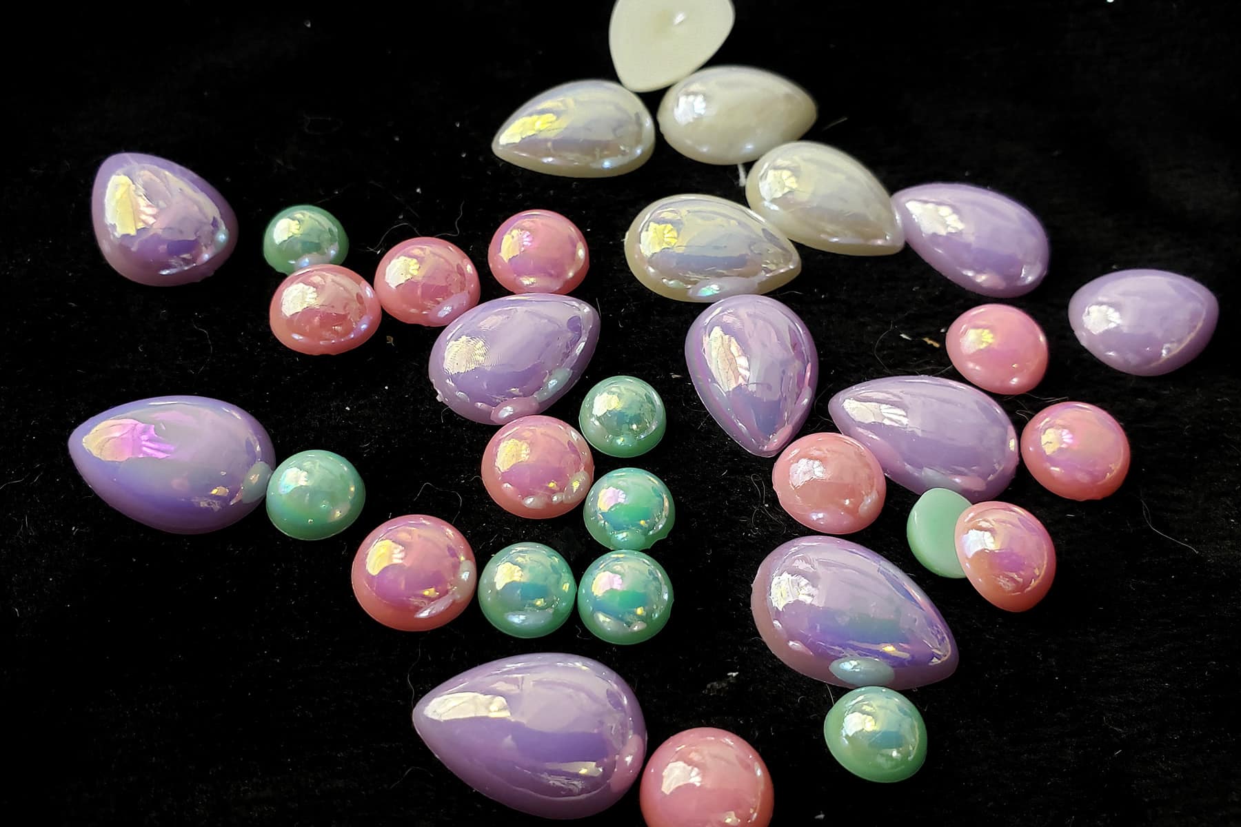 A handful of small, pearl-finished pastel stones in white, pink, mint green, and lavender.