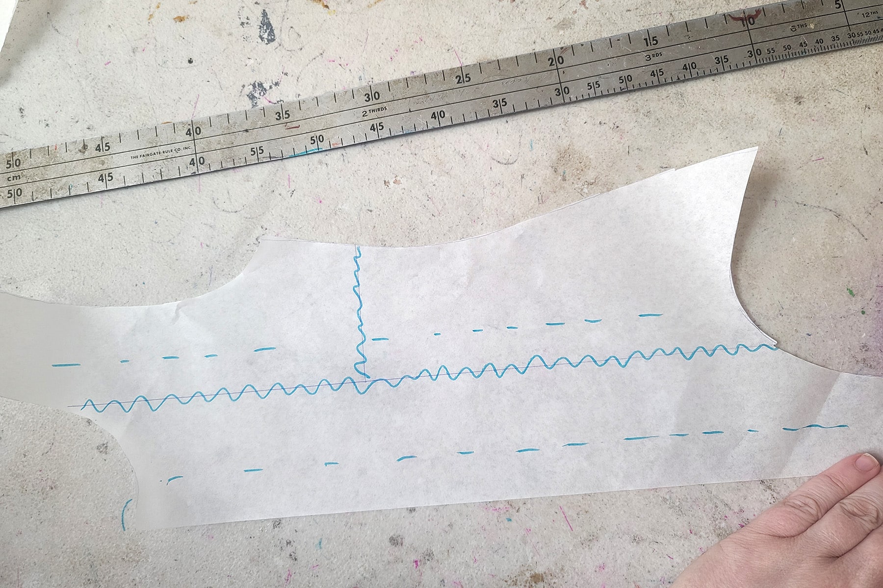 The leotard pattern piece now has a bright blue wavy line drawn over each of the design lines that divided it into 3 sections.