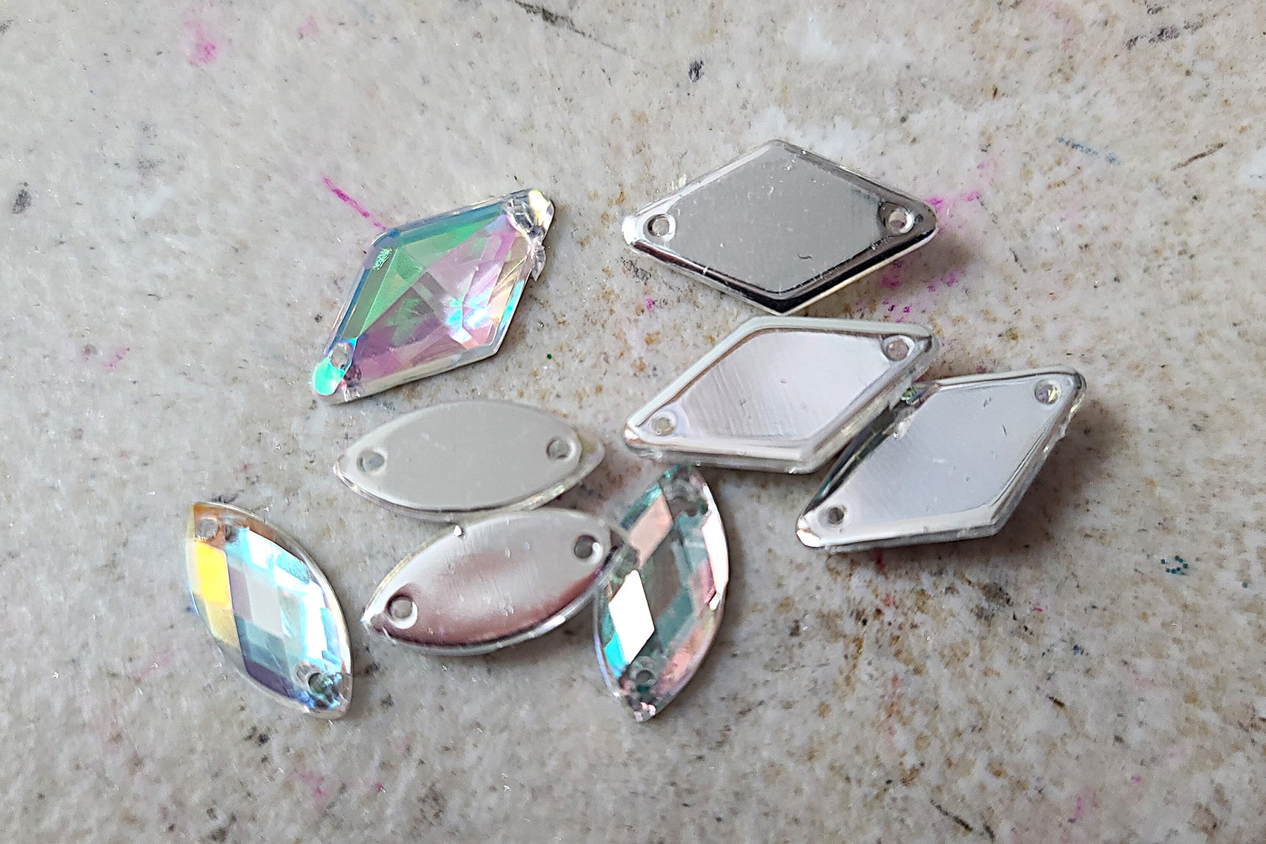 A small handful of diamond shaped iridescent rhinestones. Each has two holes in it, for sewing them on to a garment.