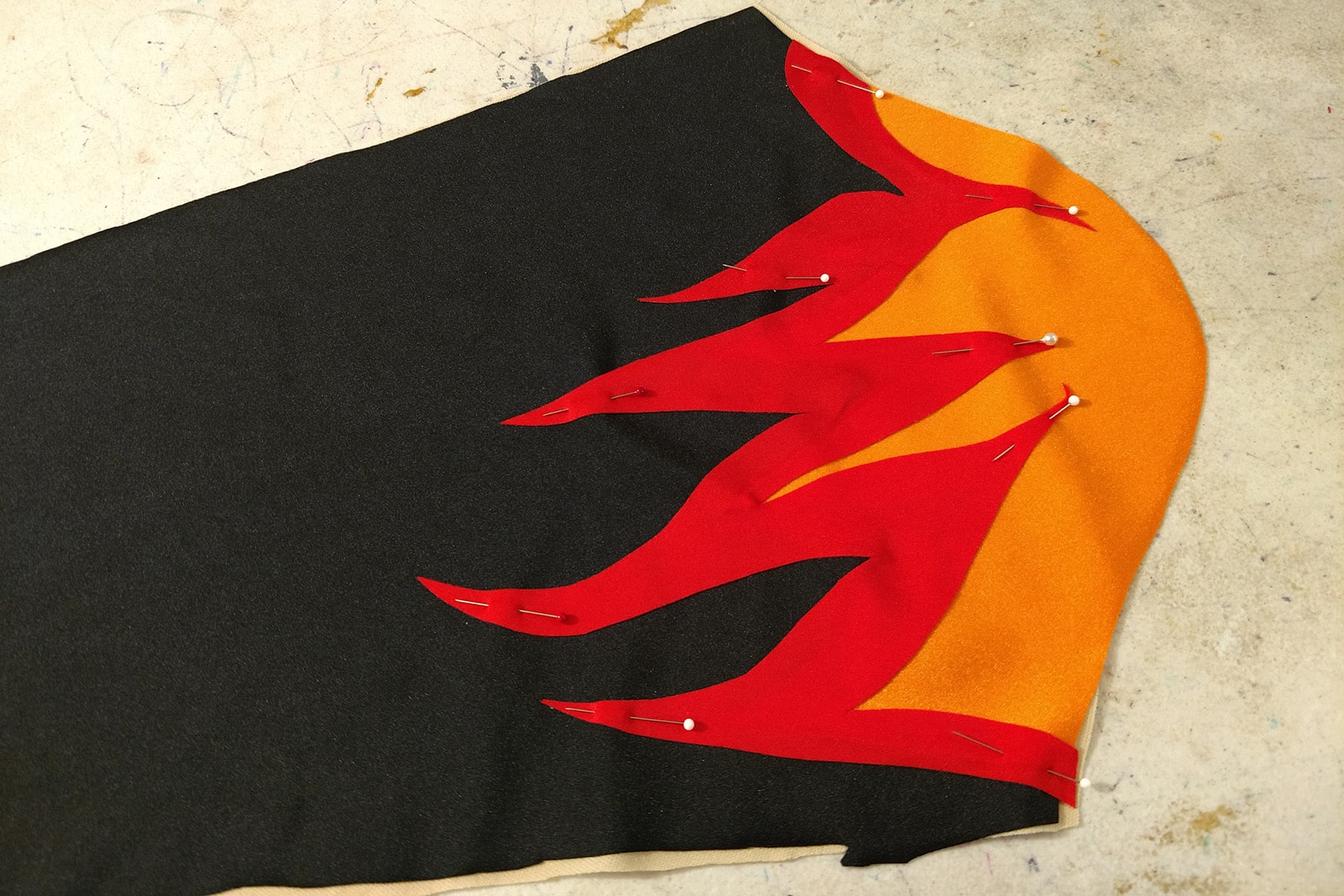 A black, red, and orange sleeve piece, pinned together.