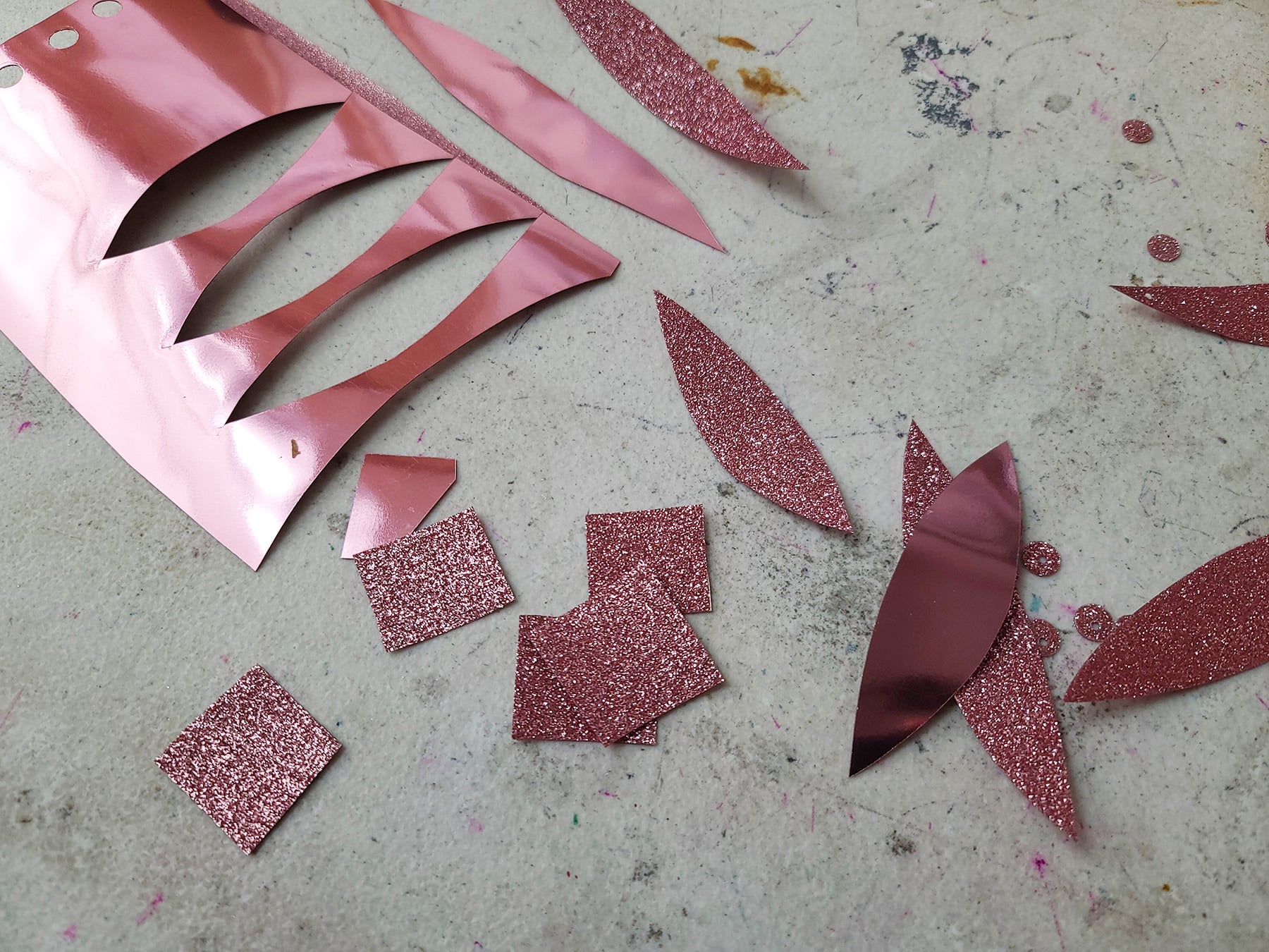 A piece of metallic pink heat transfer vinyl with lead and square shapes cut out of it.