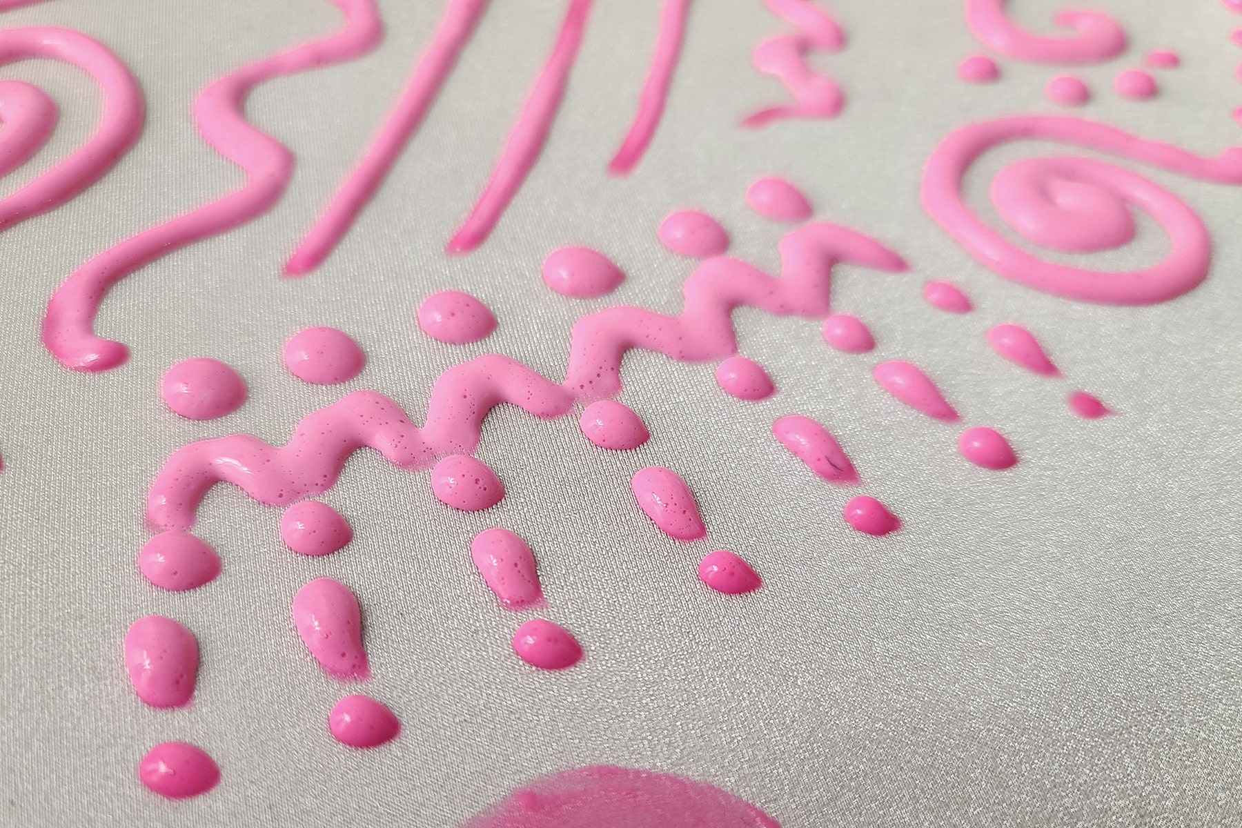 A close up view of some piped neon pink stretch paint. The paint in the foreground is partially dry, and darker than the rest of the paint.