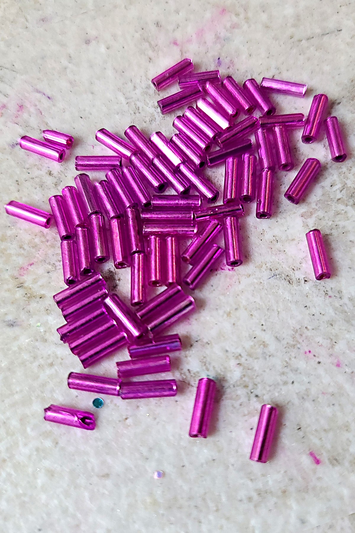 A very close up view of a pile of dark pink bugle beads.