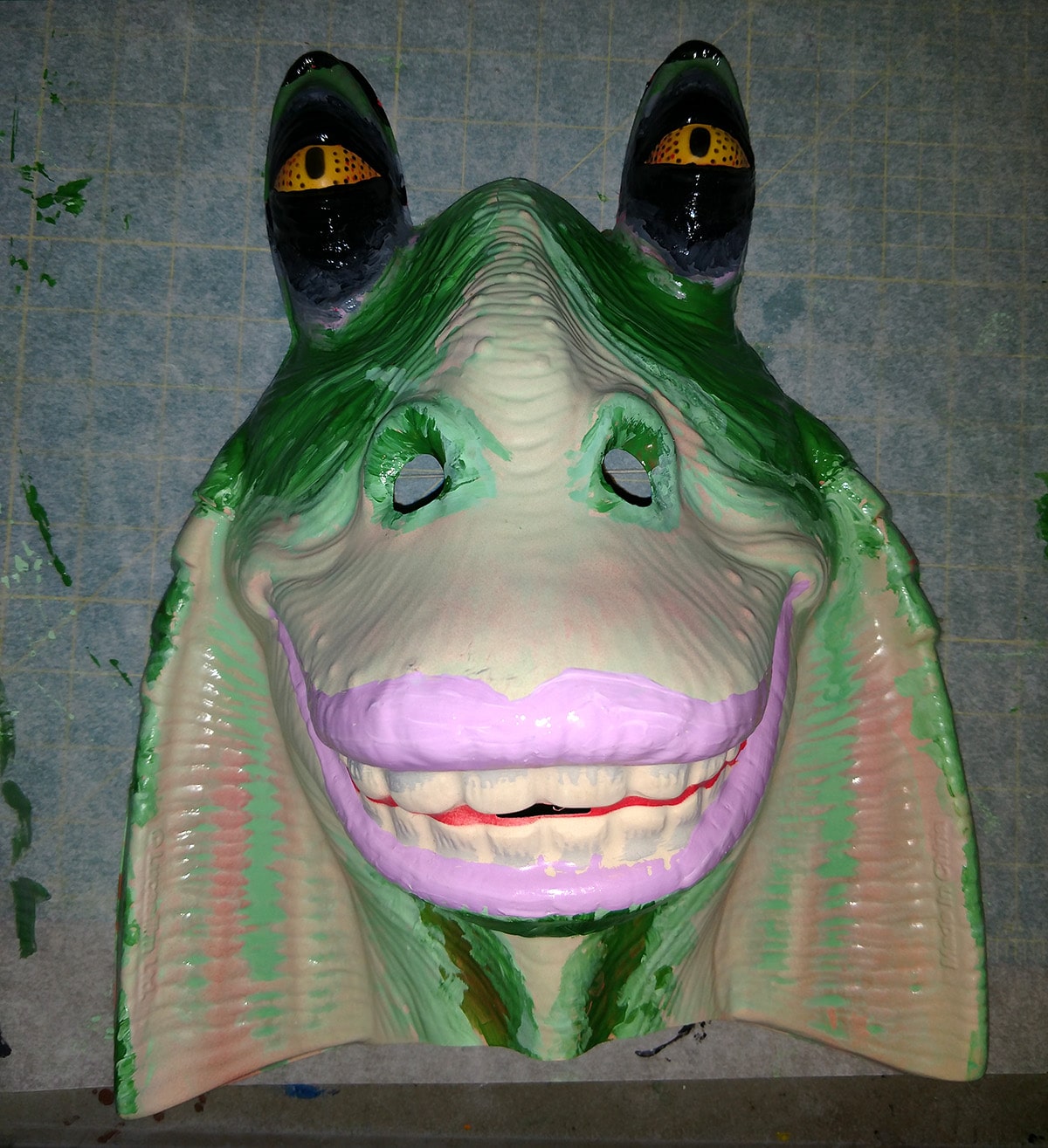 A Jar Jar Binks mask, repainted with a green and black design... and pink lipstick.