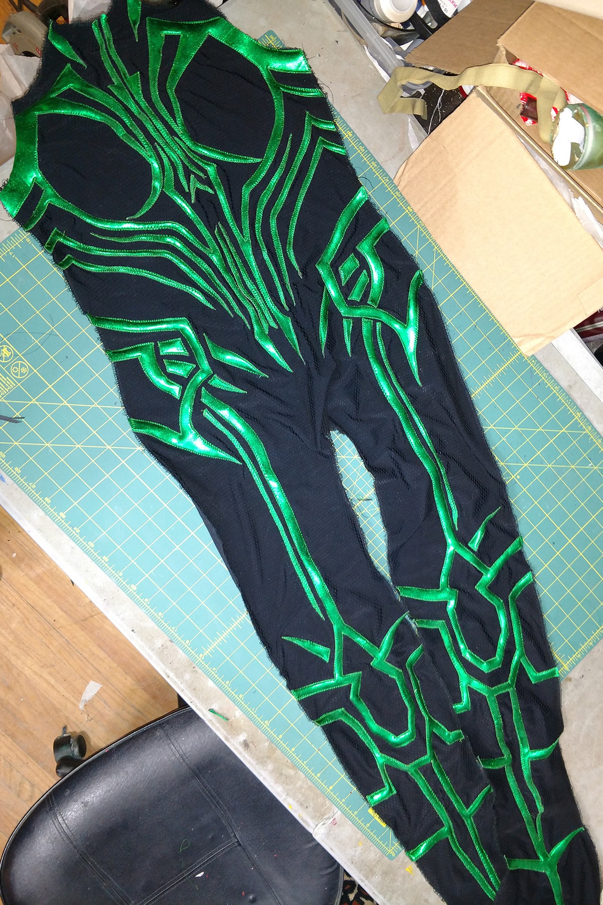 An intricate design of shiny green spandex, stitched down in place on a piece of textured black spandex - the whole front of the bodysuit.