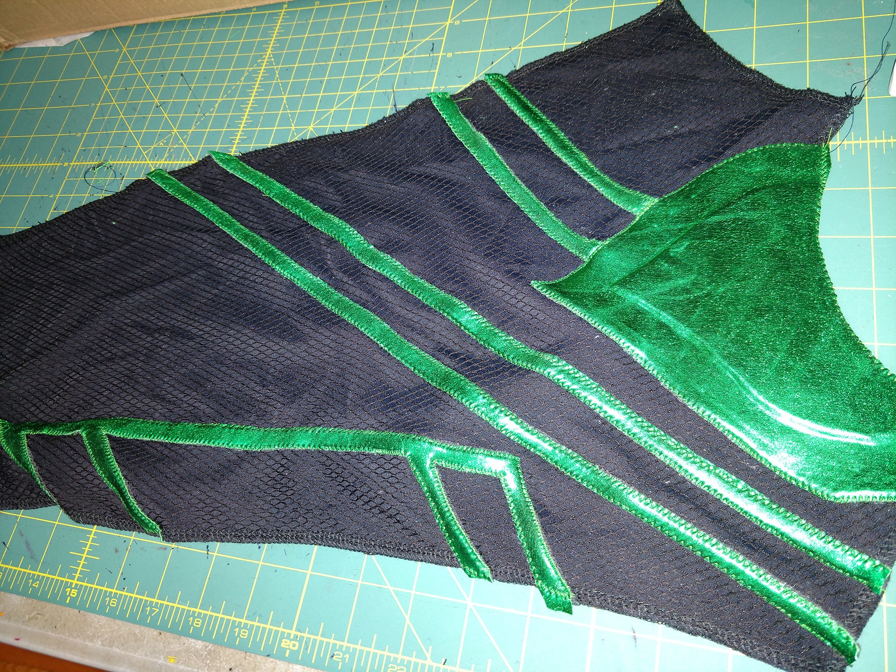 Lines of shiny green spandex, stitched down to a sleeve cut from textured black spandex.