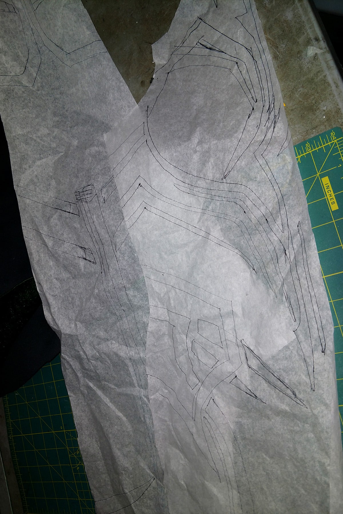 A bodysuit pattern made from exam table paper, on a green work surface.