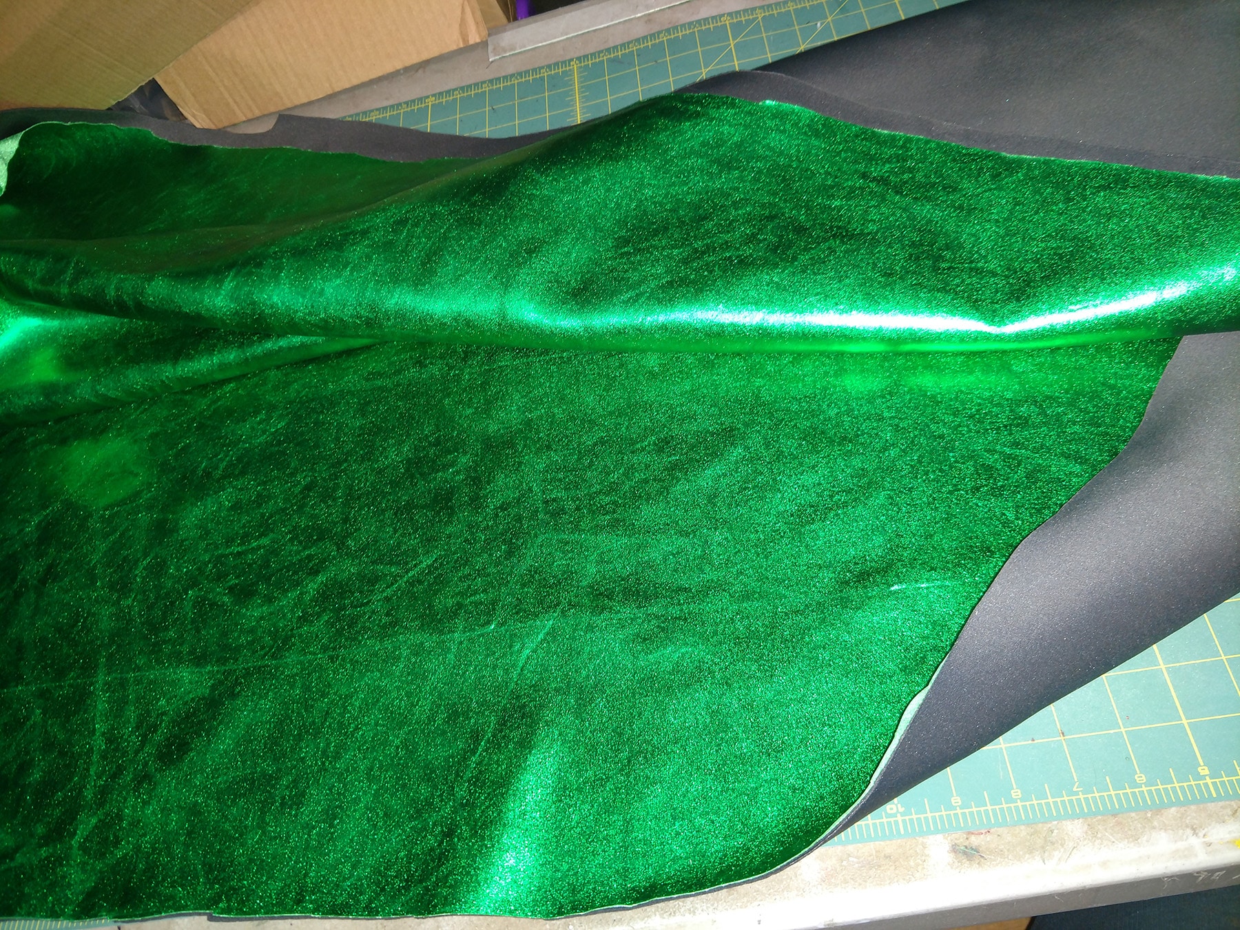 A large piece of shiny metallic green fabric. The sides are turned over, revealing grey neoprene underneath.