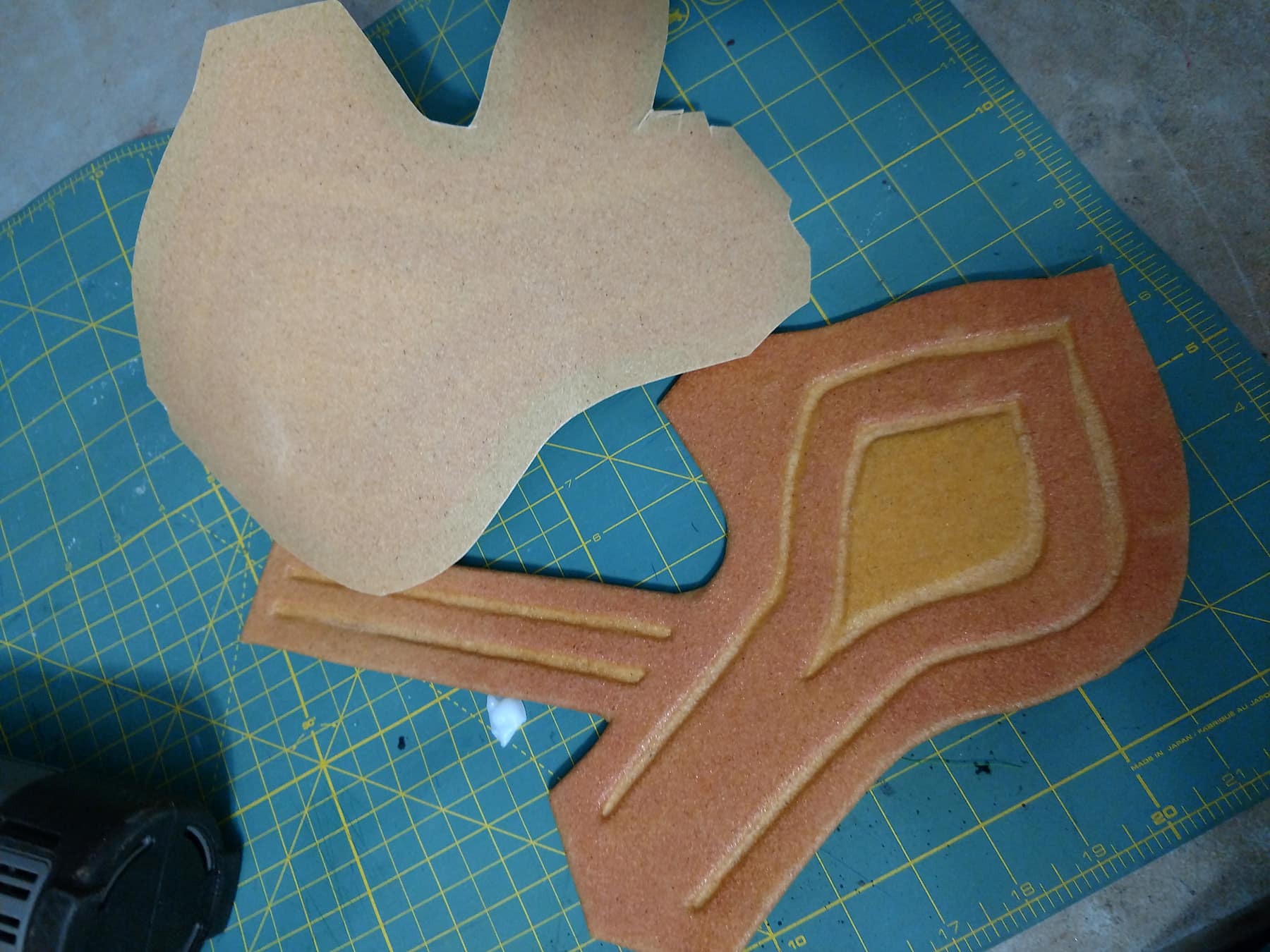 One bracer with the worbla molded down into the design is shown next to a loose piece of worbla cut to shape, ready for the second bracer.