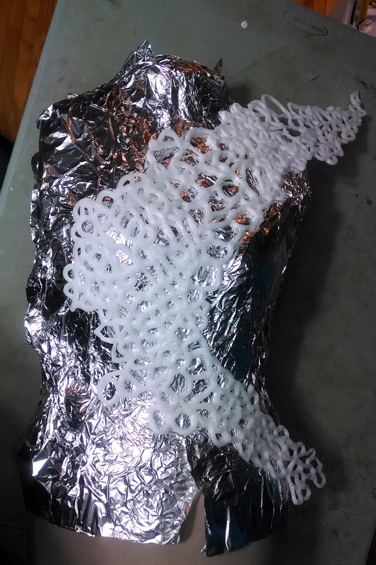 The large front piece of thermoplastic wing is being molded over a dress form covered in foil.