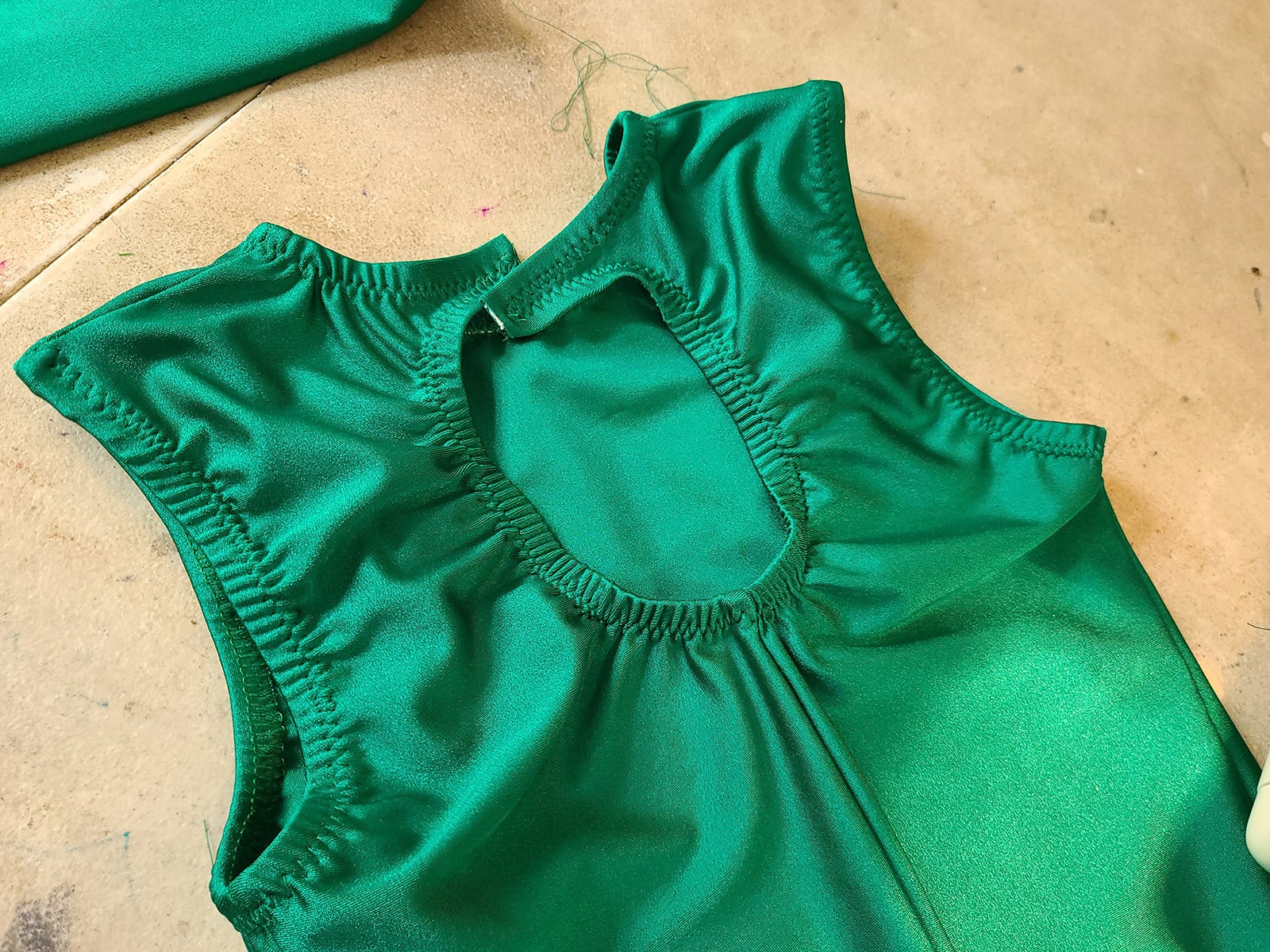 The bodice of a green skating dress with elastic sewn into the arm holes and neckline.
