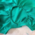 A green swimsuit with elastic applied to the neckline and keyhole back entry.