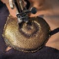 A close up photo of a gold shell applique being stitched down to a black background.