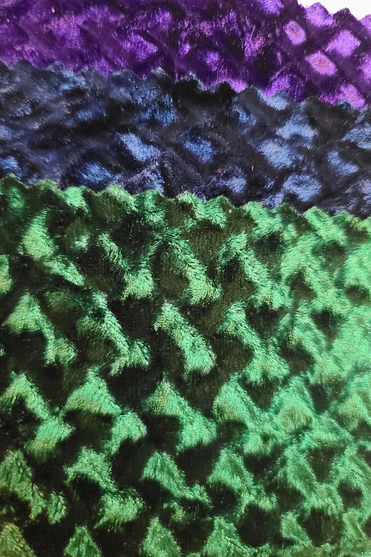 Pieces of purple, navy, and green stretch velvet with a pyramid texture to it.