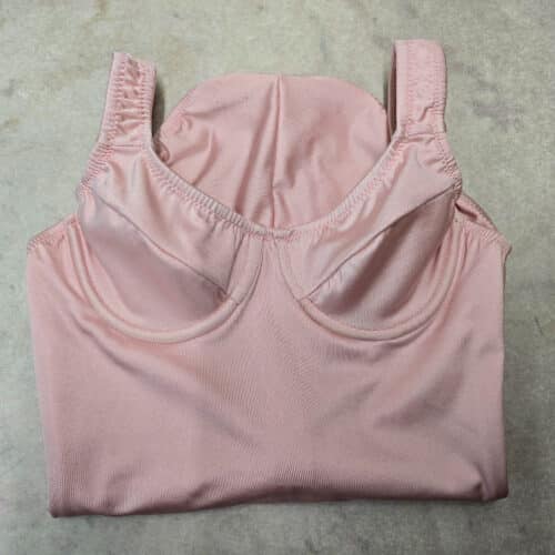 A pink underwire bodysuit on a work surface.