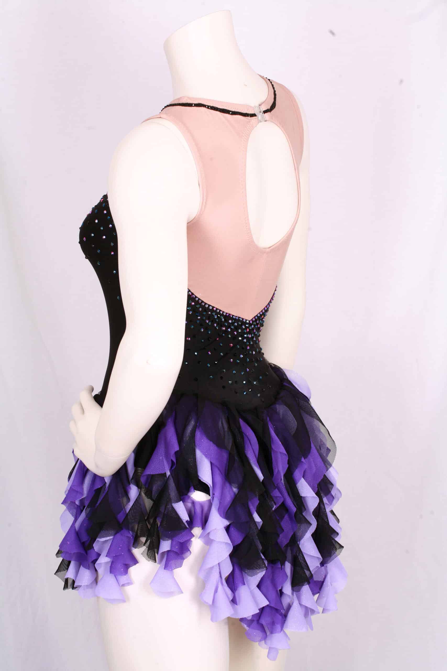 Close up view of an Ursula Dress on a mannequin.  It's a rhinestoned black figure skating dress with purple and black waterfall skirt.