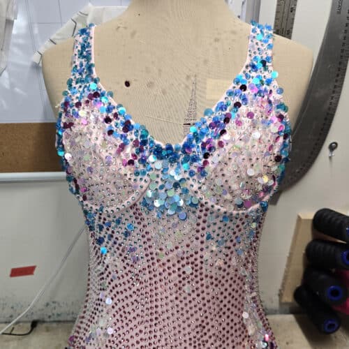 A close up photo of a sparkling pink and blue bodysuit with crystals, sequins, and beads.