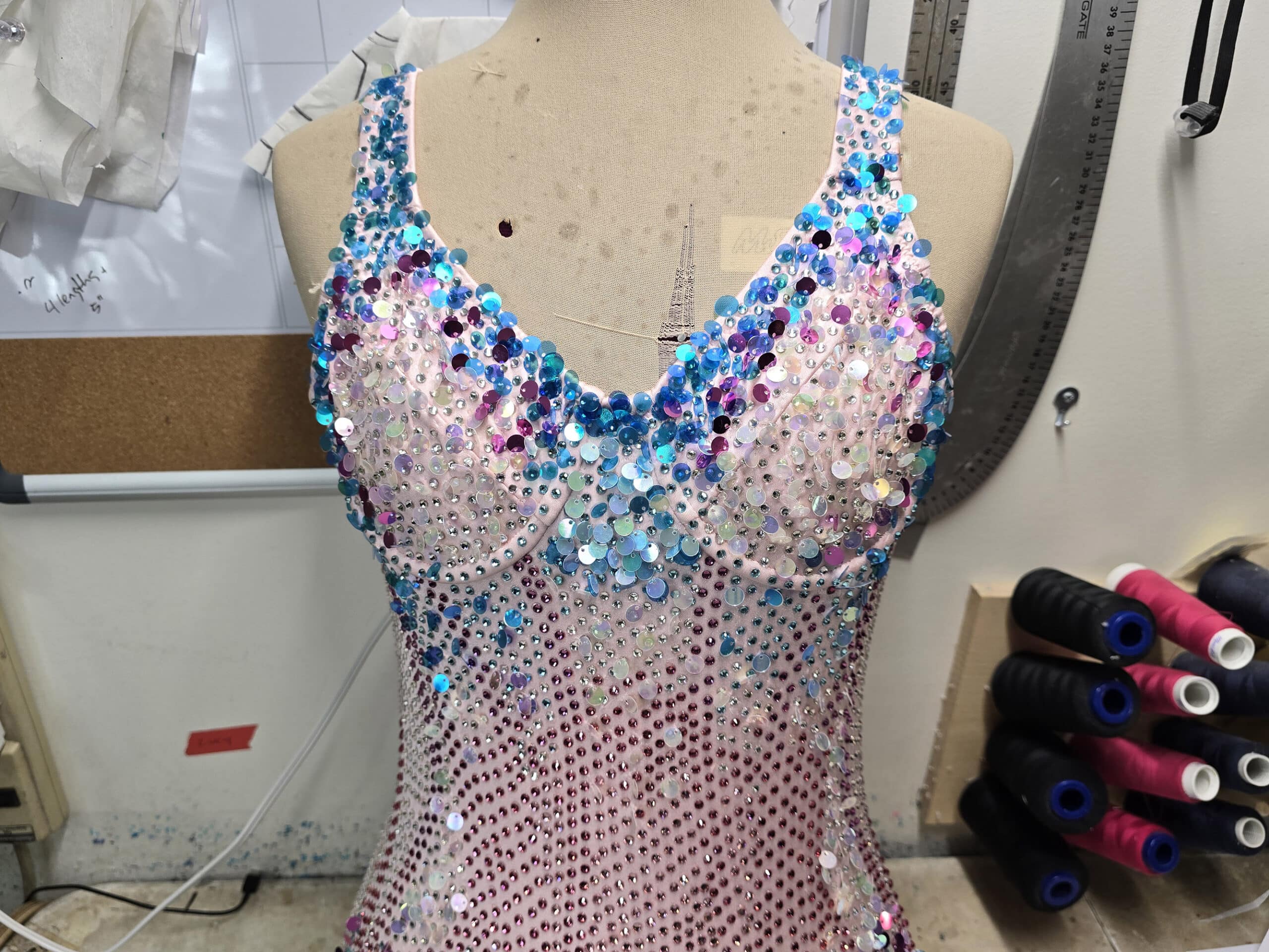 A close up photo of a sparkling pink and blue bodysuit with crystals, sequins, and beads.